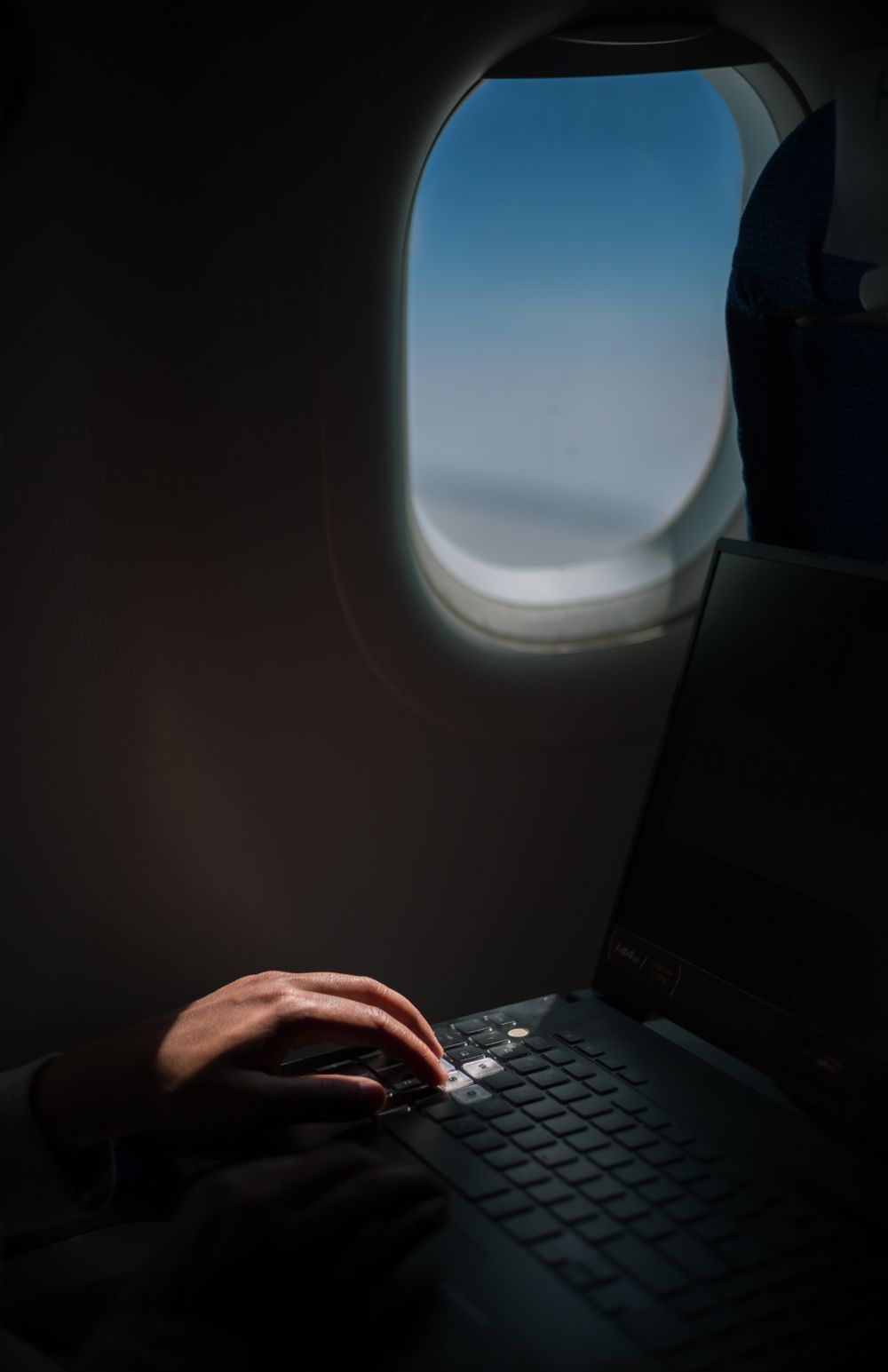 Business traveler working on a laptop beside an airplane window