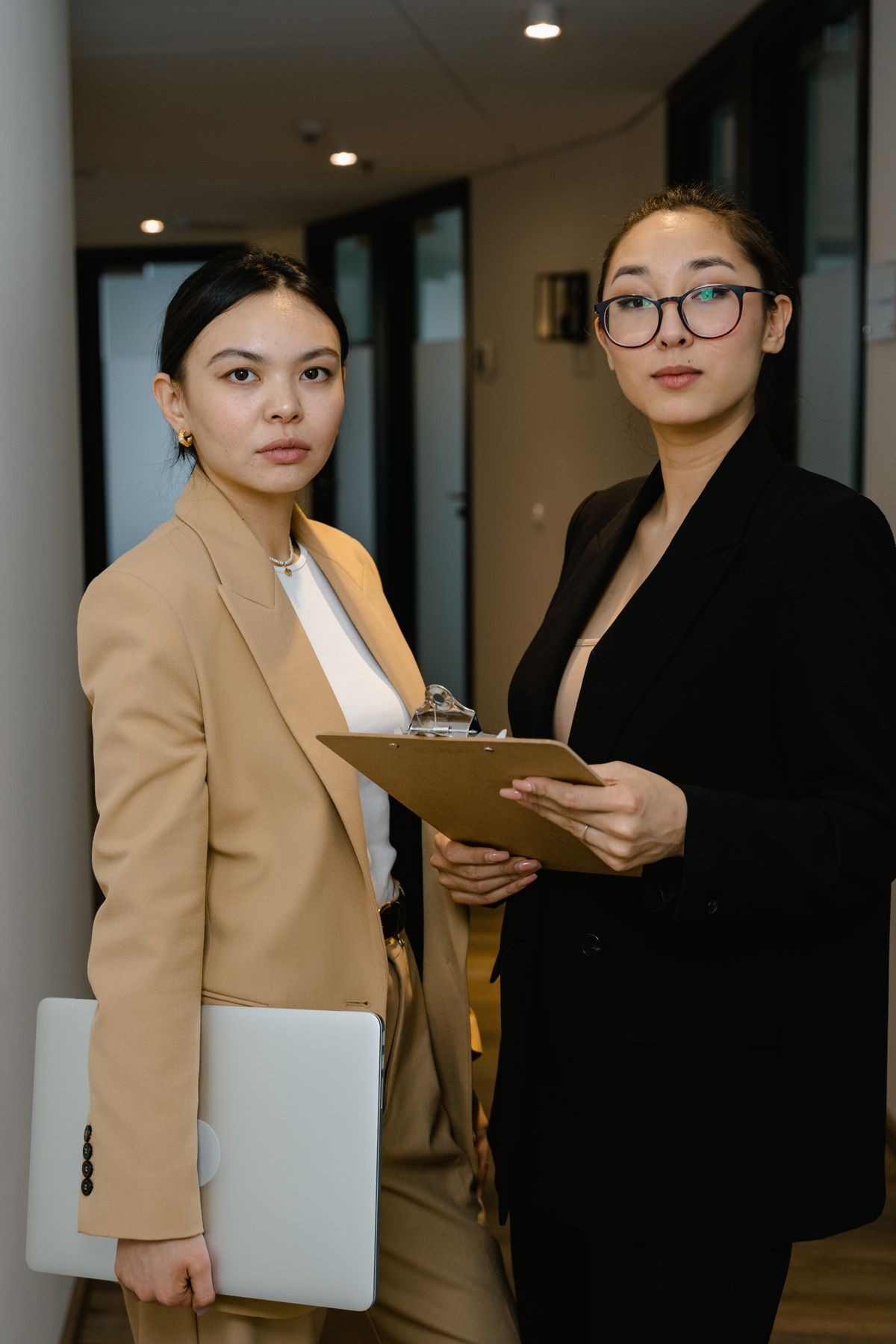 Two professionals with a clipboard and laptop in an office